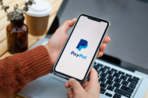 Person hält Smartphone mit PayPal-Seite in den Händen