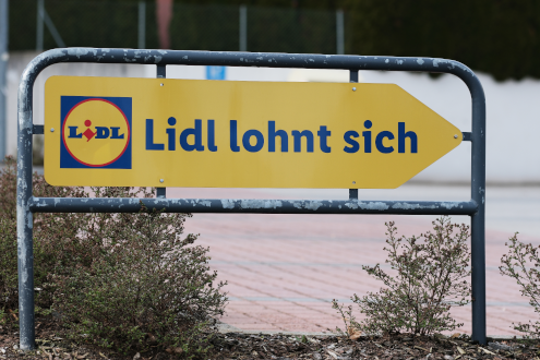 gelbes Schild auf Lidlparkplatz mit blauer Aufschrift "Lidl lohnt sich"